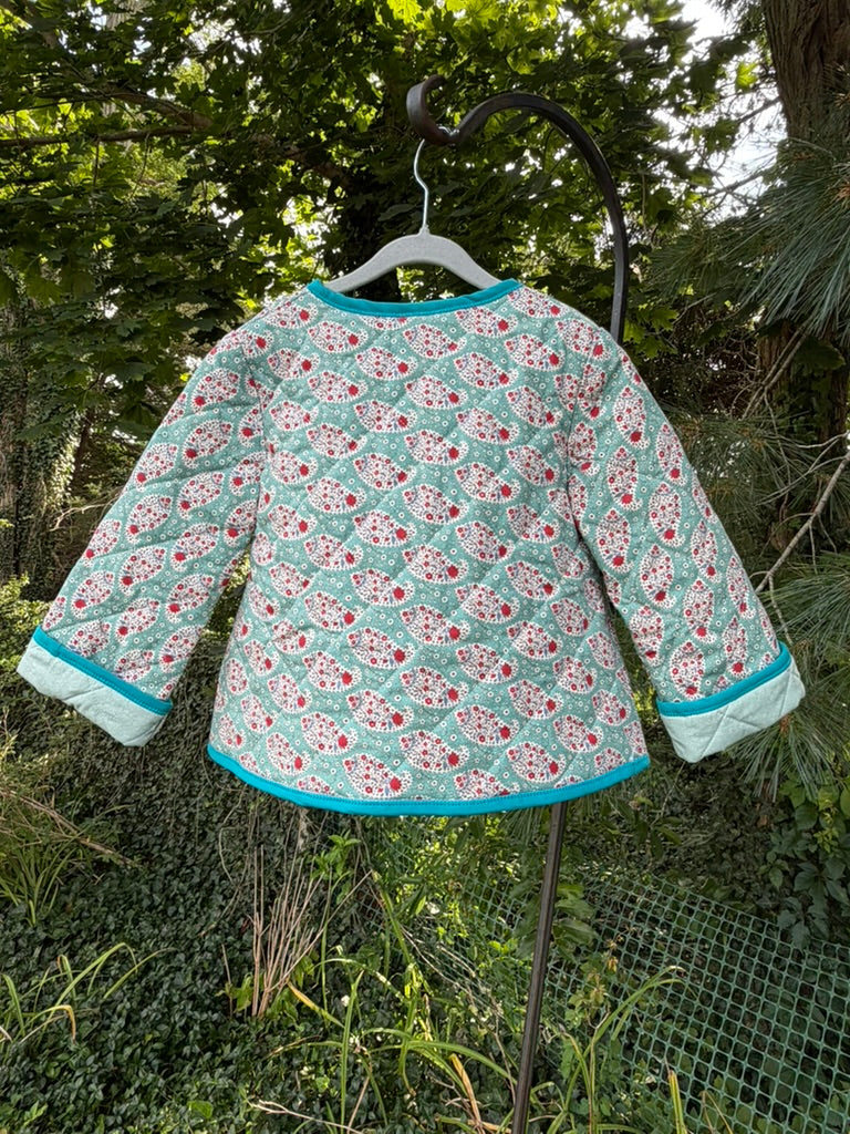 Back view of Teal Paisley Quilted Jacket size 4T — teal paisley quilted cotton with teal binding and sage green lining visible at cuffs