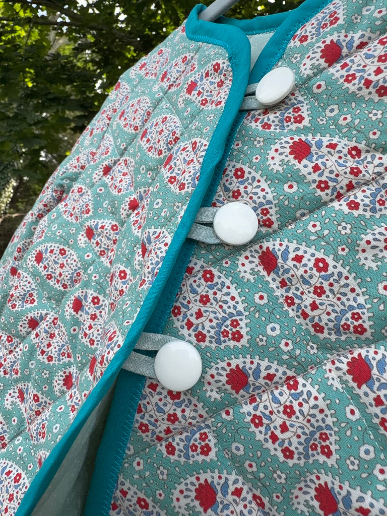 Close-up of Teal Paisley Quilted Jacket size 4T front placket — bright teal binding and round white buttons on teal paisley quilted fabric