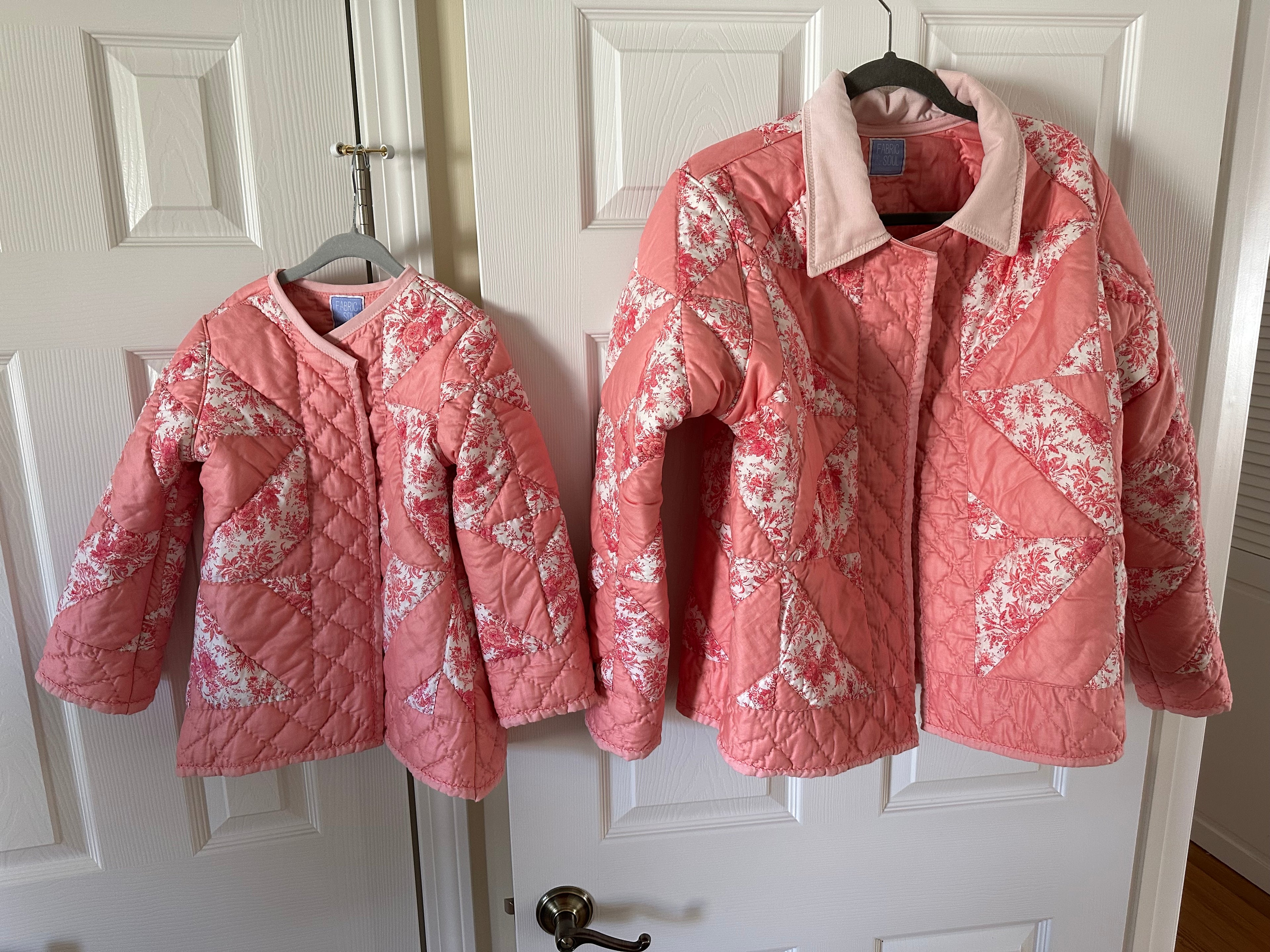 The Chatham Quilt mother and daughter coats displayed together on hangers — matching peach pink patchwork pinwheel design, Fabric & Soul Signature Collection