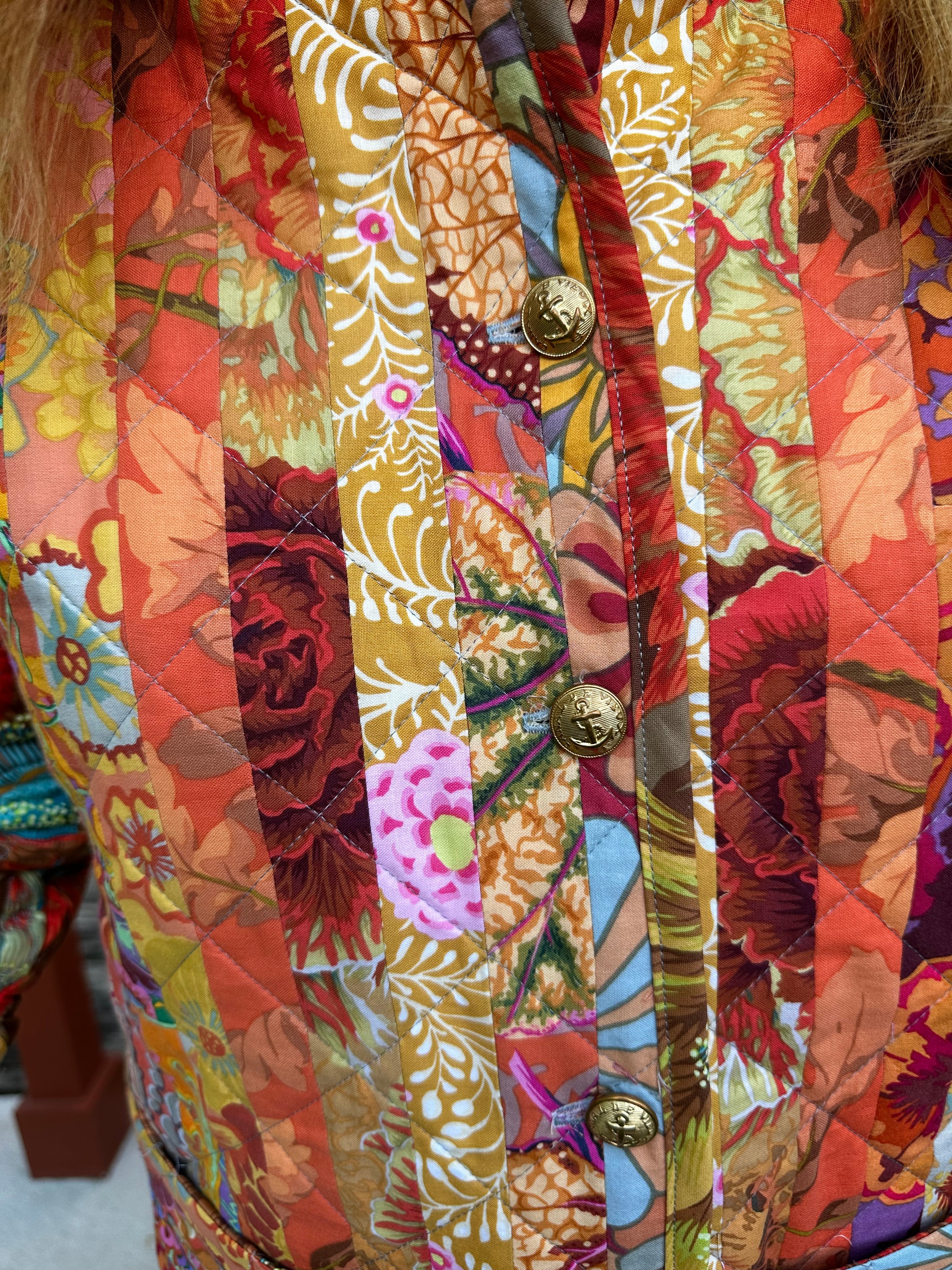 Close-up of a colorful floral-patterned quilted coat with gold military buttons.