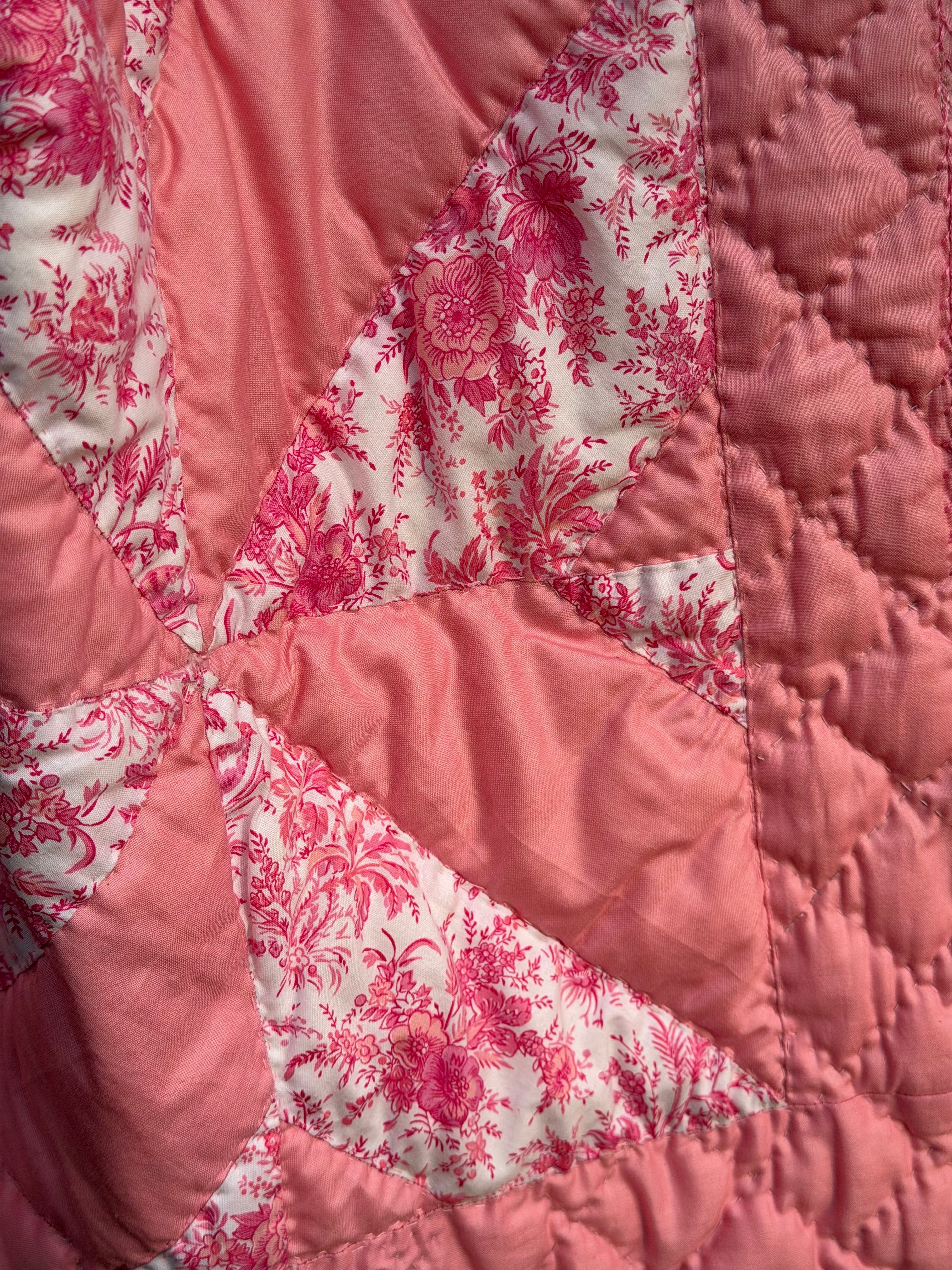 Close-up of The Chatham Quilt fabric — peach solid and white with deep pink floral toile patchwork, original hand quilting with visible pencil guide lines