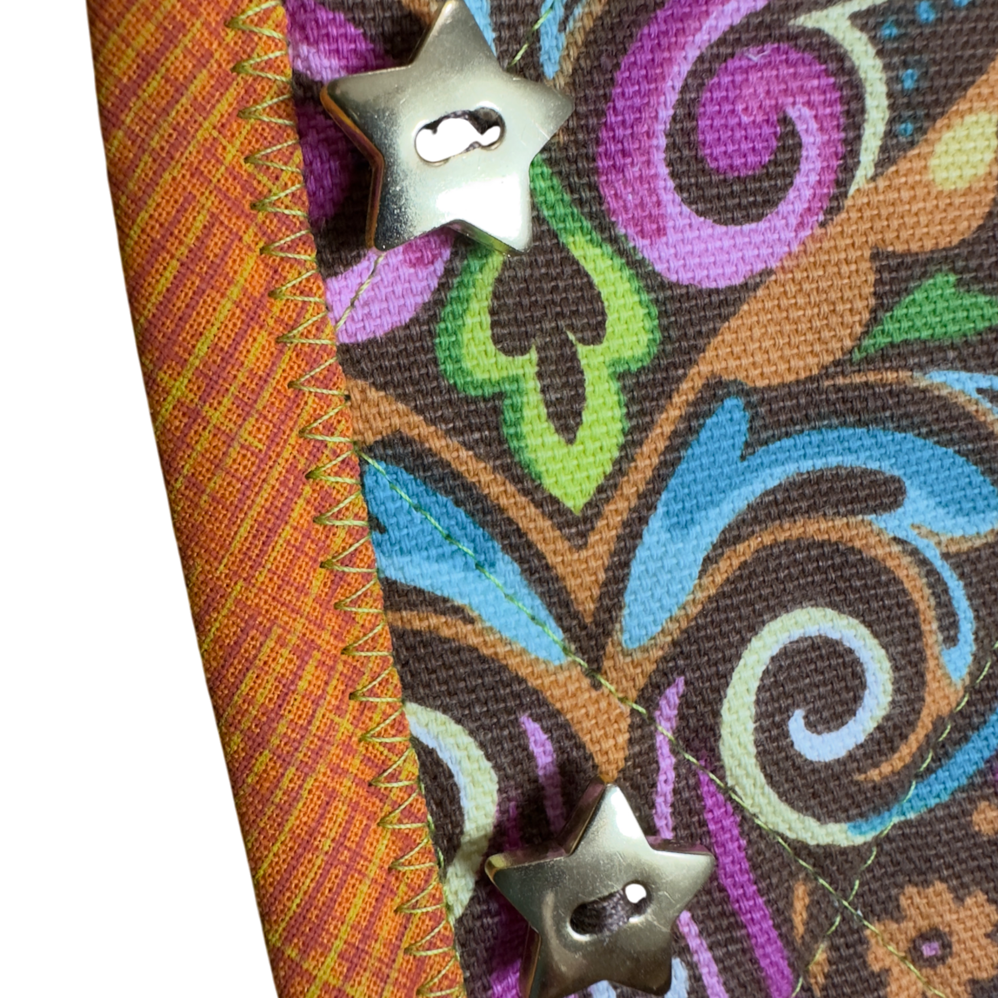 Colorful fabric with intricate patterns and star-shaped buttons and orange and yellow binding