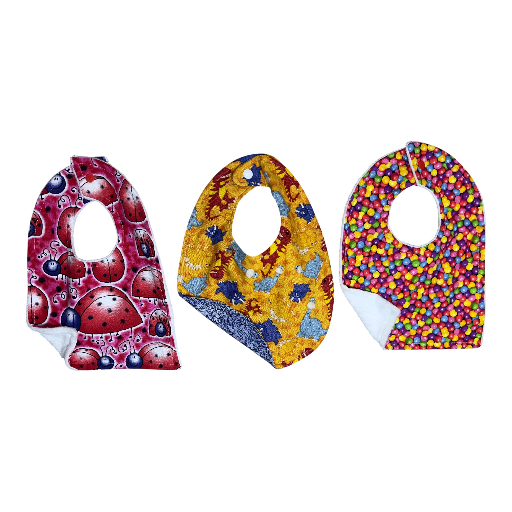 Handmade baby bib set of three with smiling ladybugs, whimsical dinosaurs, and colorful gumballs on quilting cotton