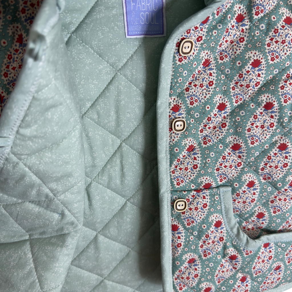 Detail of teal paisley fabric, buttons and quilted construction